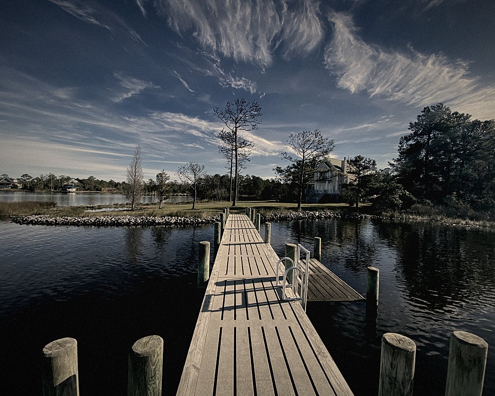 A boardwalk running out over still water under a wide sky